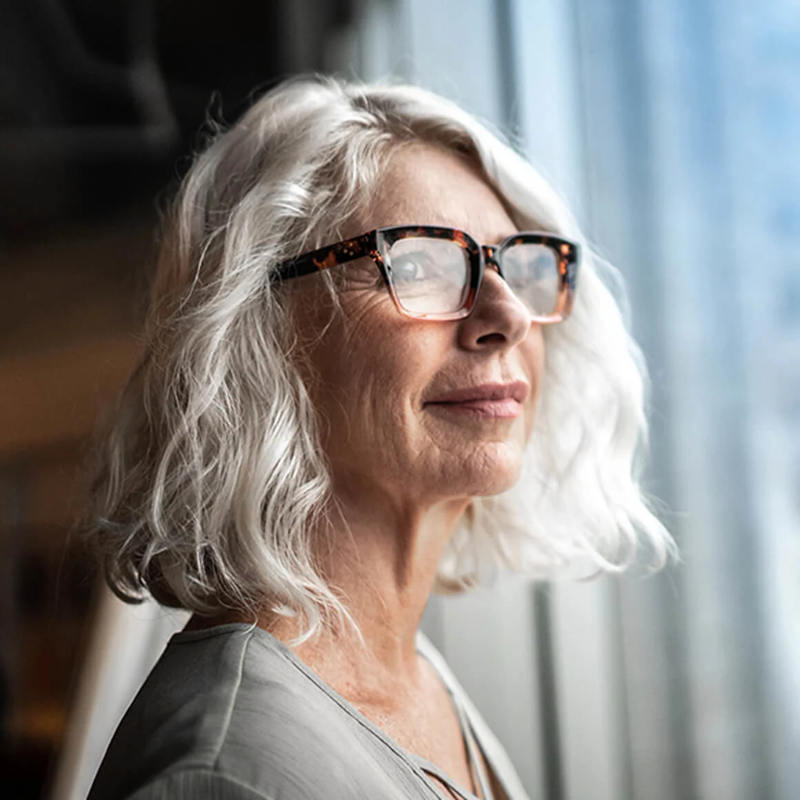 Woman with glasses standing next to window